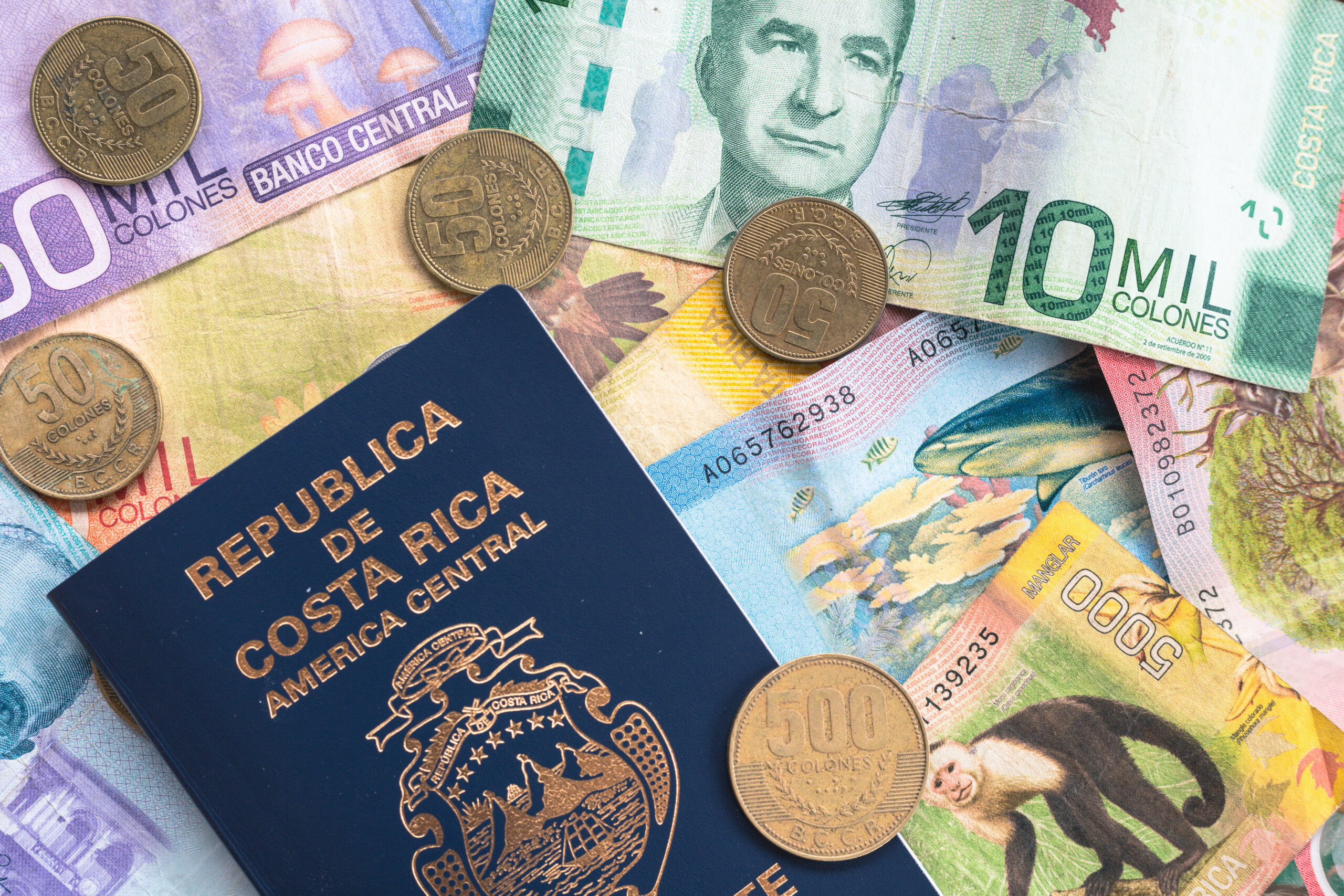 Flat lay of coin and paper currency from Costa Rica, with Costa Rican passport